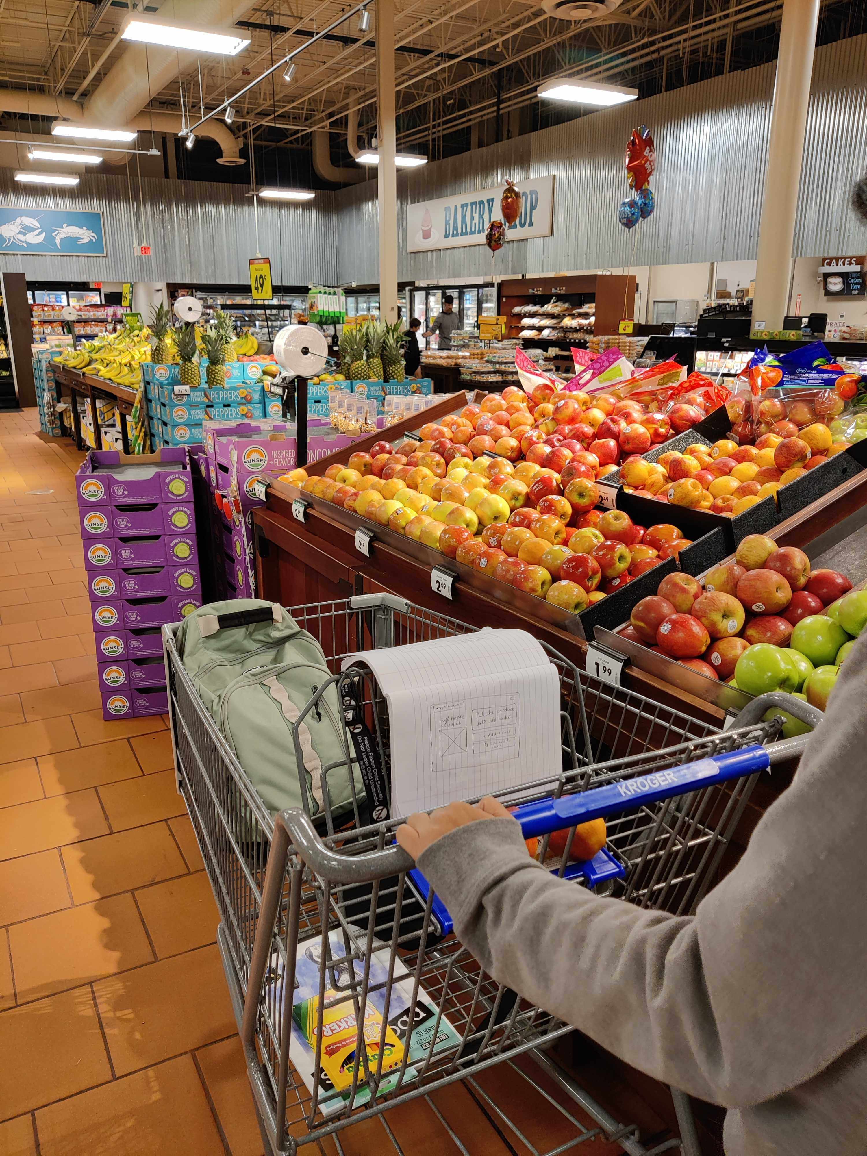 Shopper’s hands on the cart handle beside the notebook standing in for the digital screen